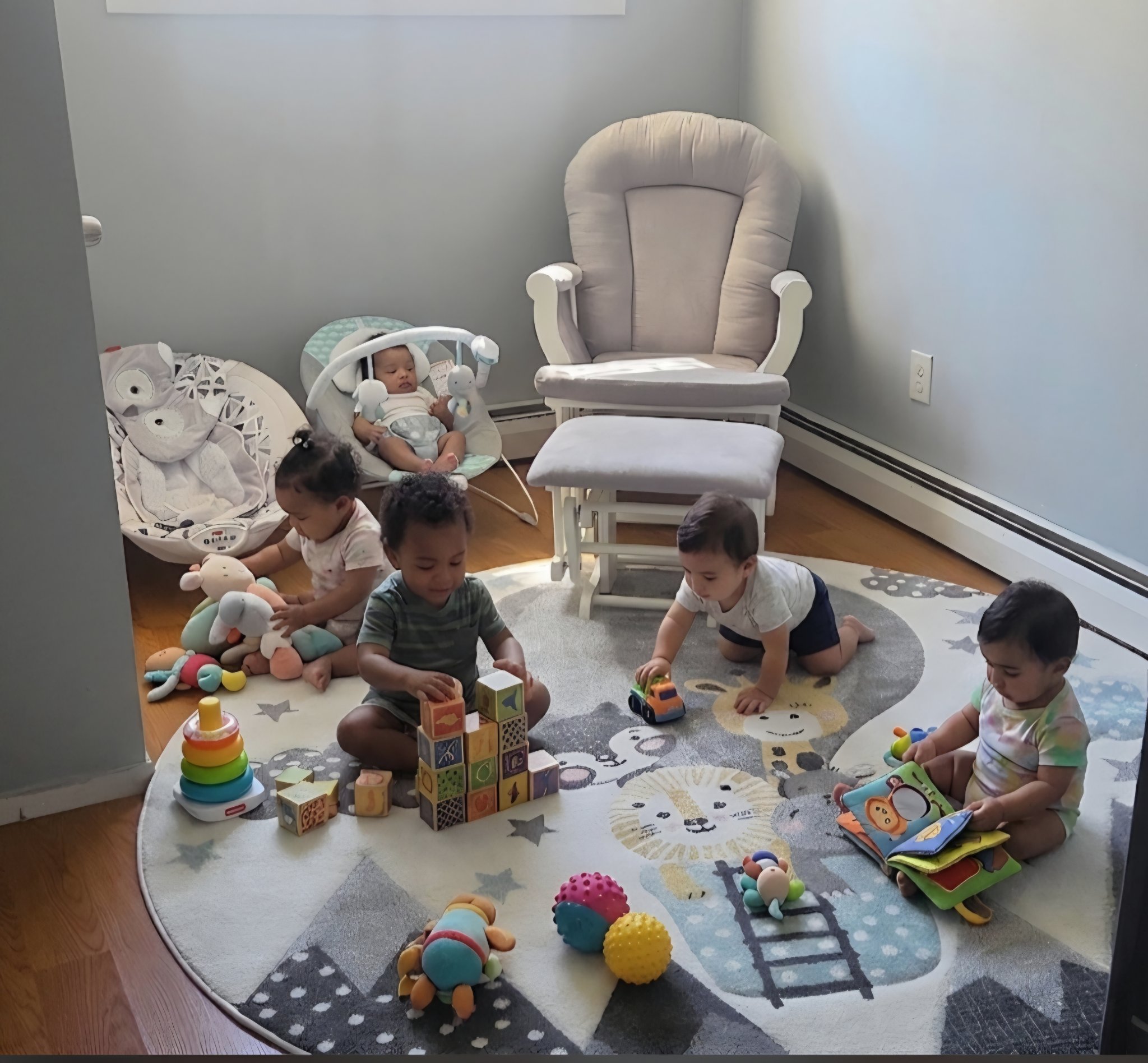 Babies and toddlers playing with blocks and toys on a cozy rug in the infant room at Taylor's Bright Beginners
